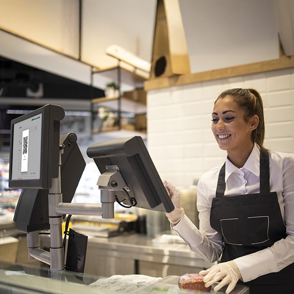 POS System A Woman Smiles At The Cash Register In A Restaurant, Efficiently Using The Paywint POS System For Transactions