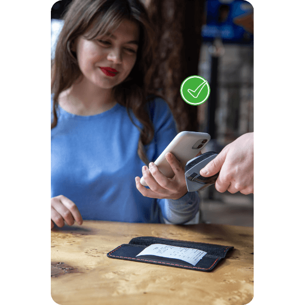 Seamless Transactions Anytime, Anywhere A Woman In A Blue Top Smiling As She Uses Her Smartphone For A Seamless Digital Payment Transaction At A Restaurant, With A Receipt And Wallet Placed On The Table And A Green Checkmark Indicating Successful Payment