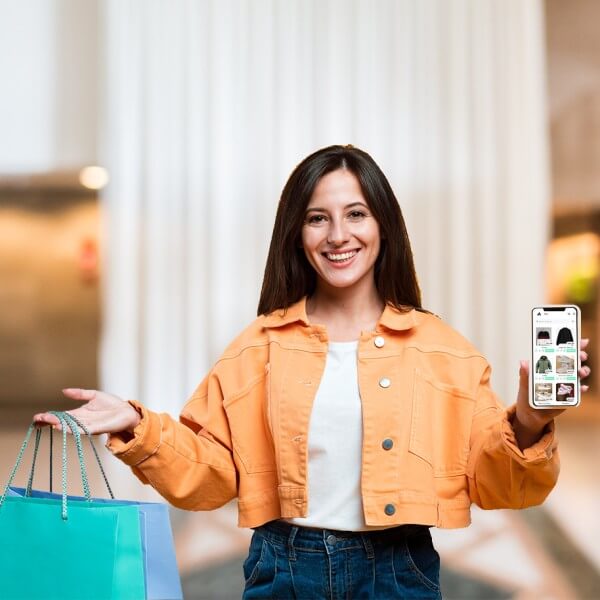 Shopping Store A Woman Holding a Smartphone Displaying the Paywint Online Store While Packaging a Product. She Is Sitting with a Laptop, Managing Her Ecommerce Business from Home
