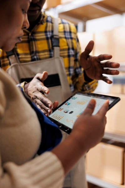 Gain Insights and Make Smarter Decisions Two Warehouse Employees Analyzing Data on a Tablet for Inventory Management
