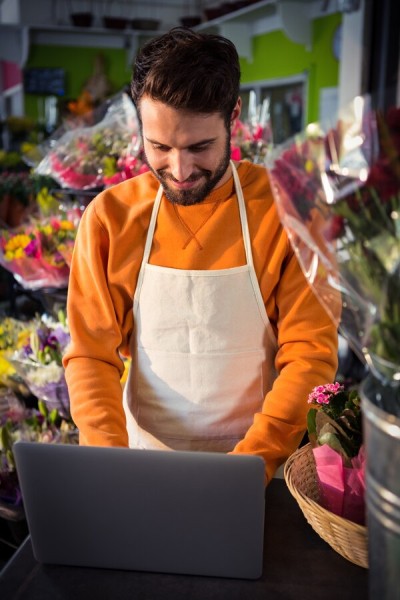 Secure and Scalable Sales Management Small Business Owner Using a Digital Payment System on a Laptop in a Flower Shop