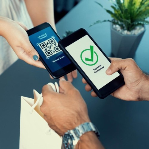 Send Money Easily and Securely with Modern Payment Solutions Two People Demonstrating How To Send Money Digitally: One Smartphone Shows A QR Code For Scanning, While The Other Displays A 'Payment Completed' Message With A Green Checkmark. A Shopping Bag Exchange Highlights A Successful Transaction