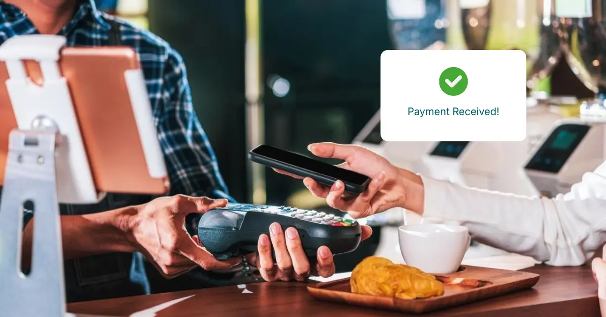 A Person Using a Mobile Phone to Make a Payment at a Café, with a Payment Terminal Displaying Confirmation